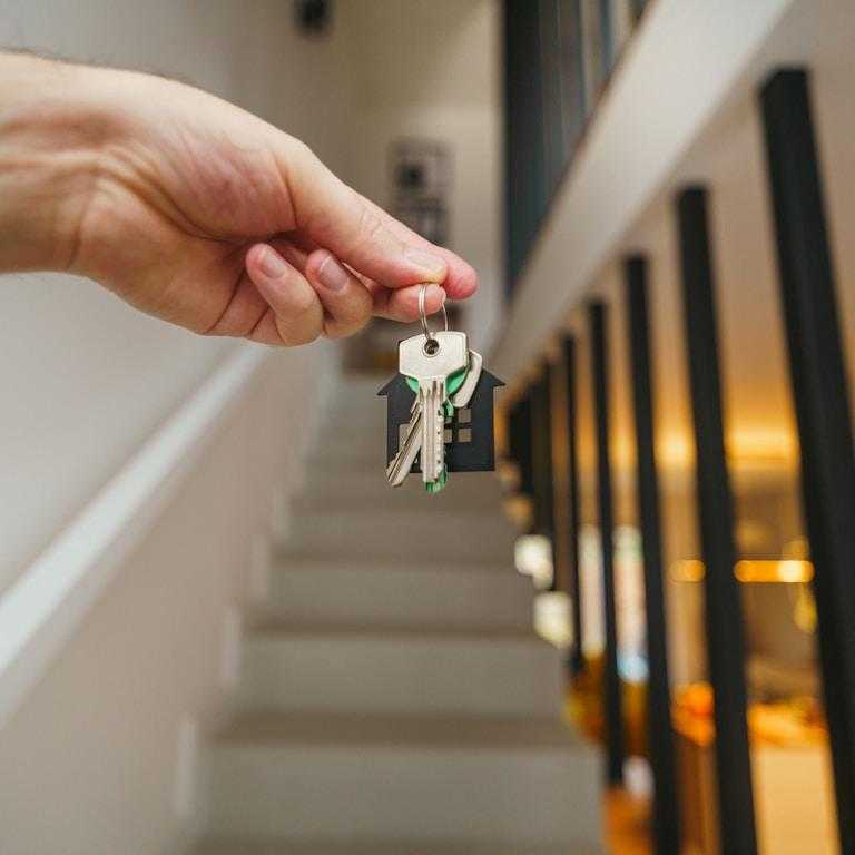 Here's a possible caption: keys being held in front of a staircase.